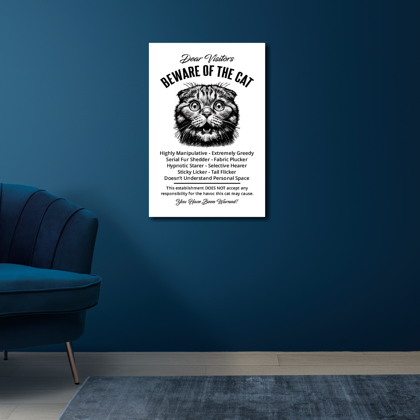 16 inch by 24 inch canvas print of a funny Scottish Fold 'Beware of the cat' notice. Mounted on a blue wall above a blue chair.