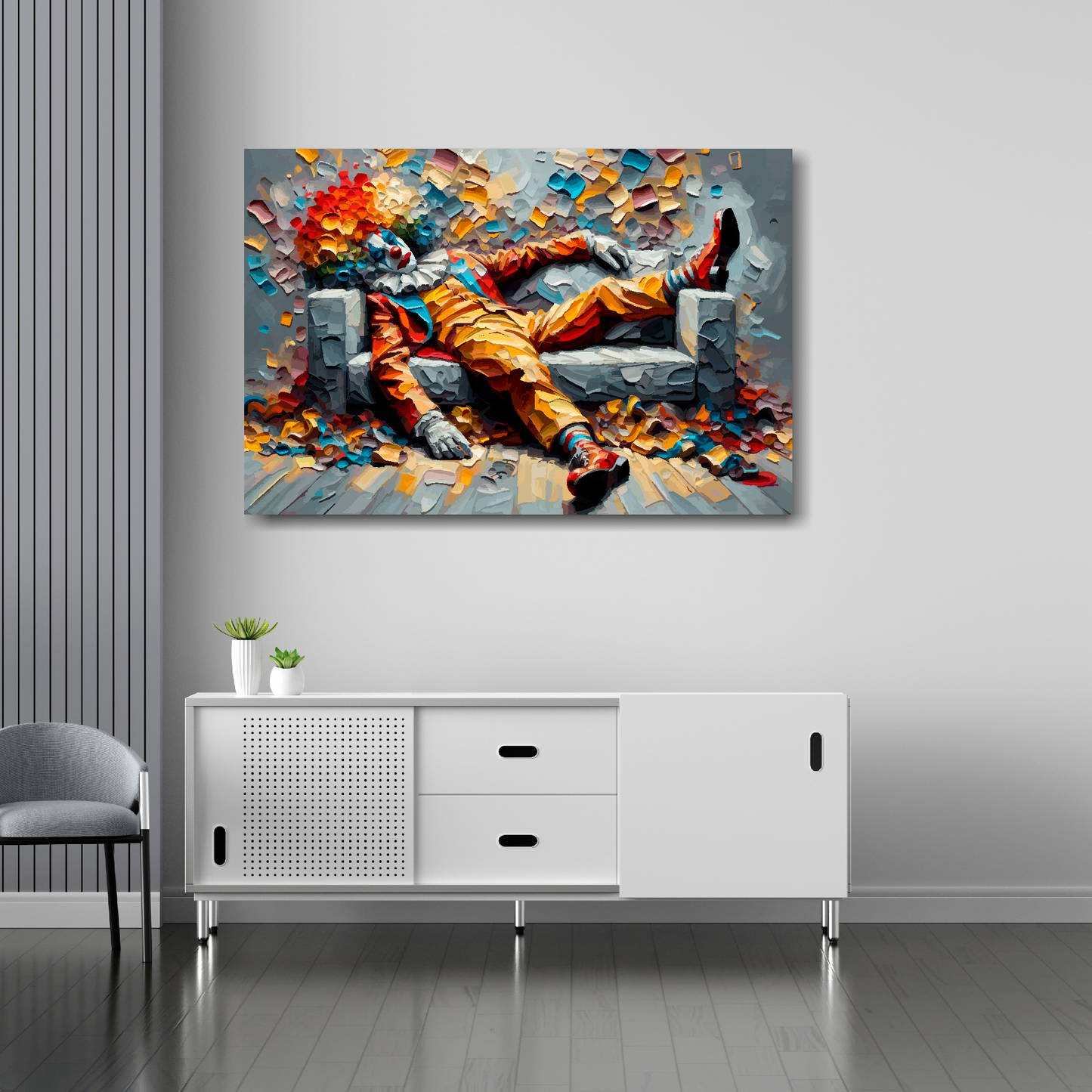 36 inch by 24 inch abstract canvas print of a colourful clown laying on a sofa. Mounted on a white wall above a white sideboard.