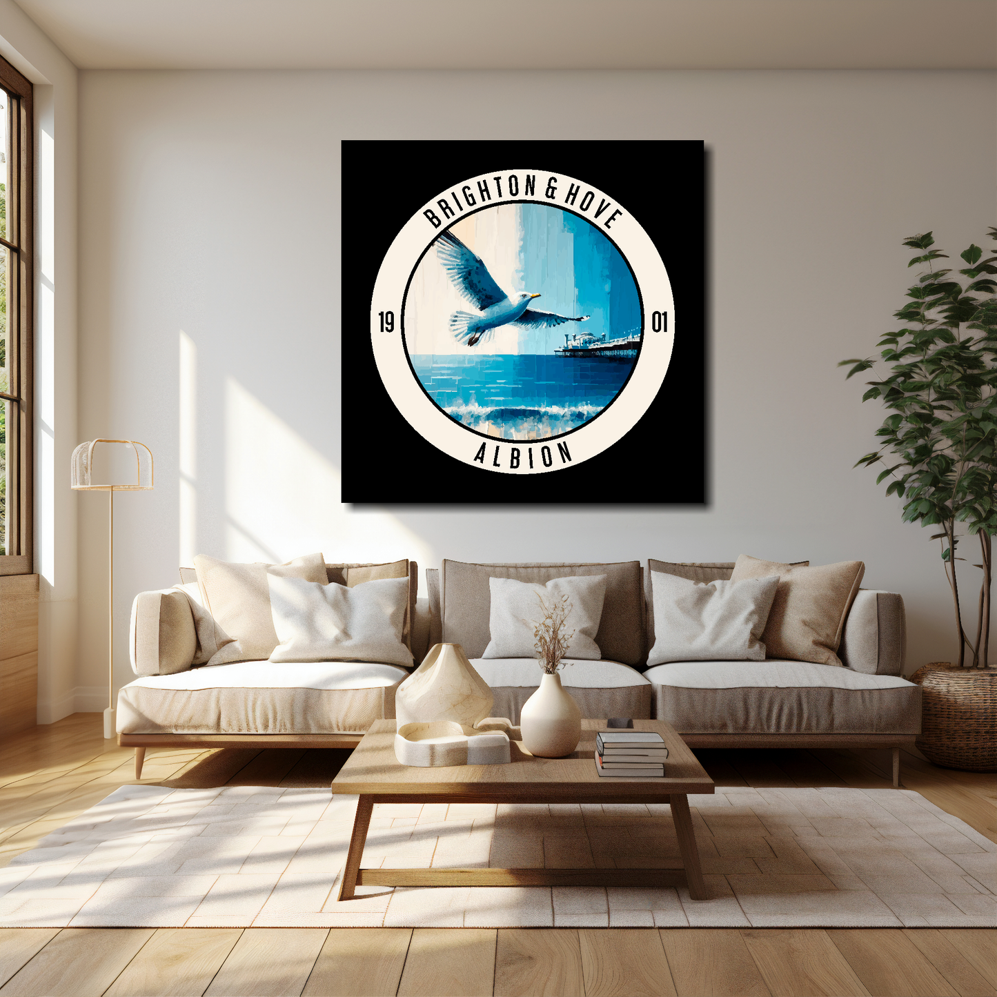 40 inch by 40 inch Brighton FC inspired canvas, featuring a large seagull, beach and pier on black background. Mounted on a white wall above a cream sofa with decorative cushions.