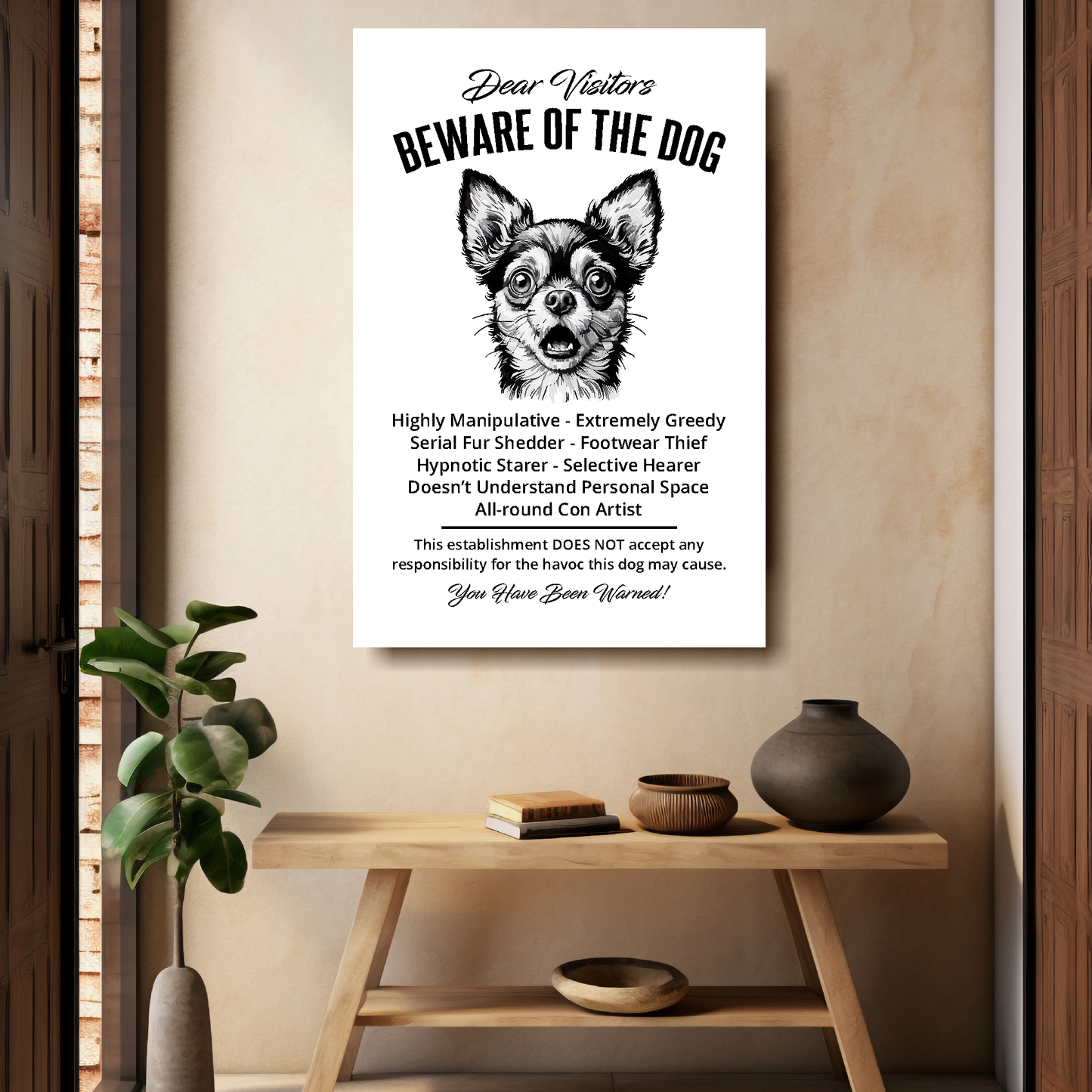 A funny Chihuahua 'Beware of the Dog' disclaimer notice. Black text and dog image on a white background. Mounted on a beige wall above a wooden bench.