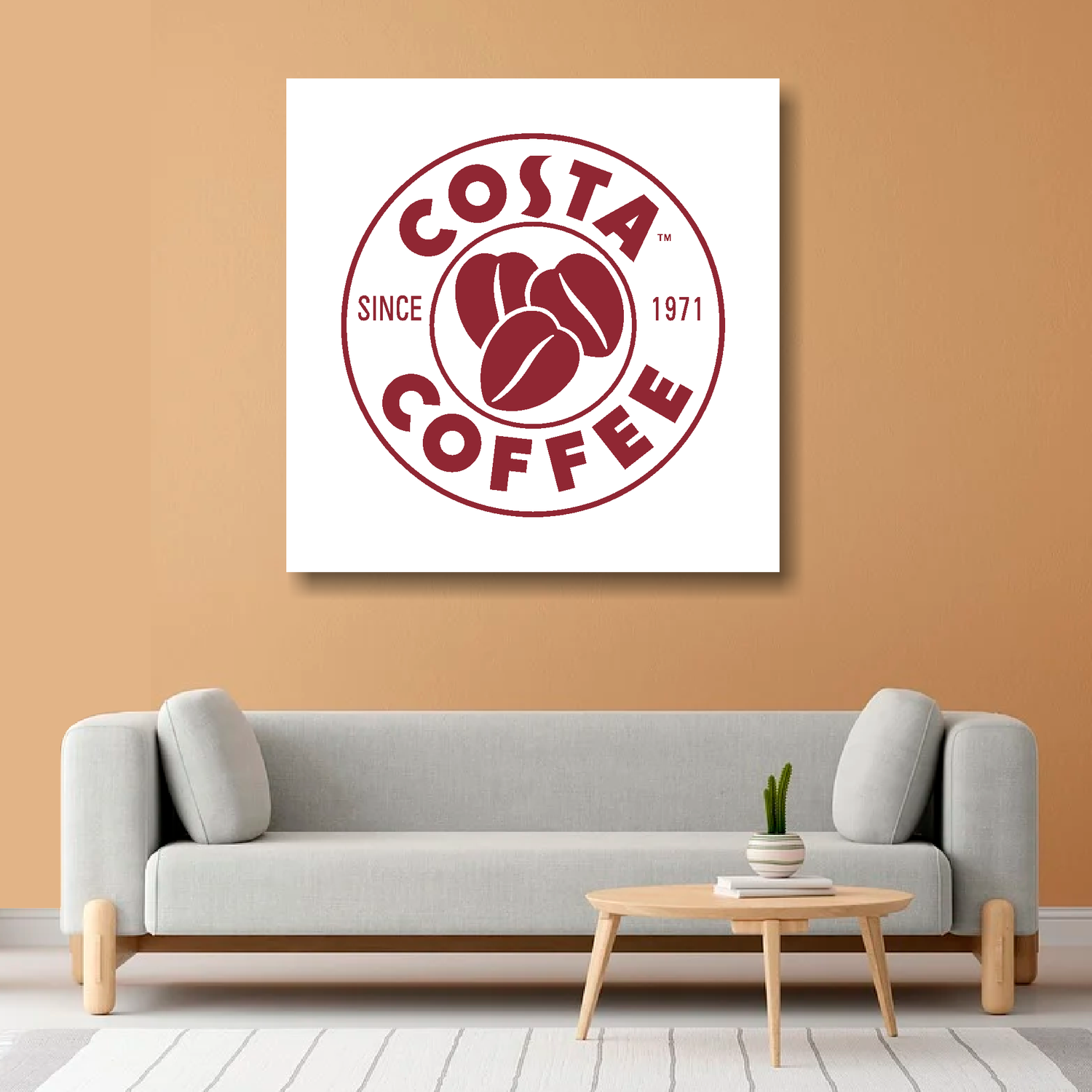 A personalised company logo on canvas, mounted on a orange wall above a gray sofa in a living room setting.