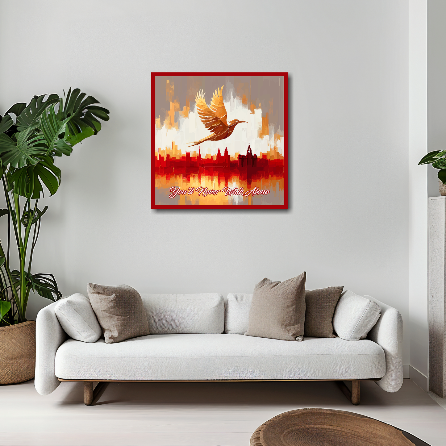 20 inch by 20 inch Liverpool FC inspired canvas, mounted on a living room wall above a white sofa, featuring a Liver bird flying over a Liverpool skyline with the words 'You'll Never Walk Alone' in red and white.