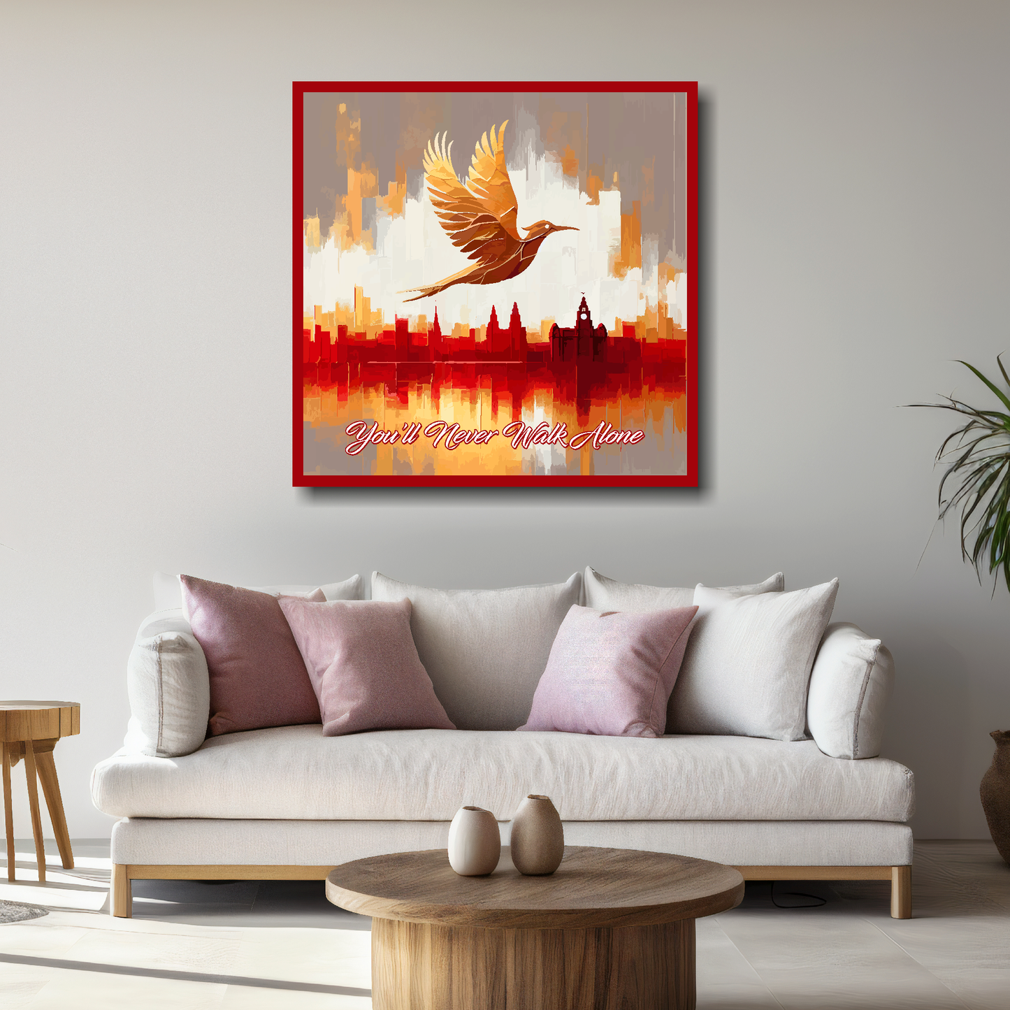 Liverpool FC inspired large canvas, mounted on a living room wall above a white sofa, featuring a Liver bird flying over a Liverpool skyline with the words 'You'll Never Walk Alone' in red and white.