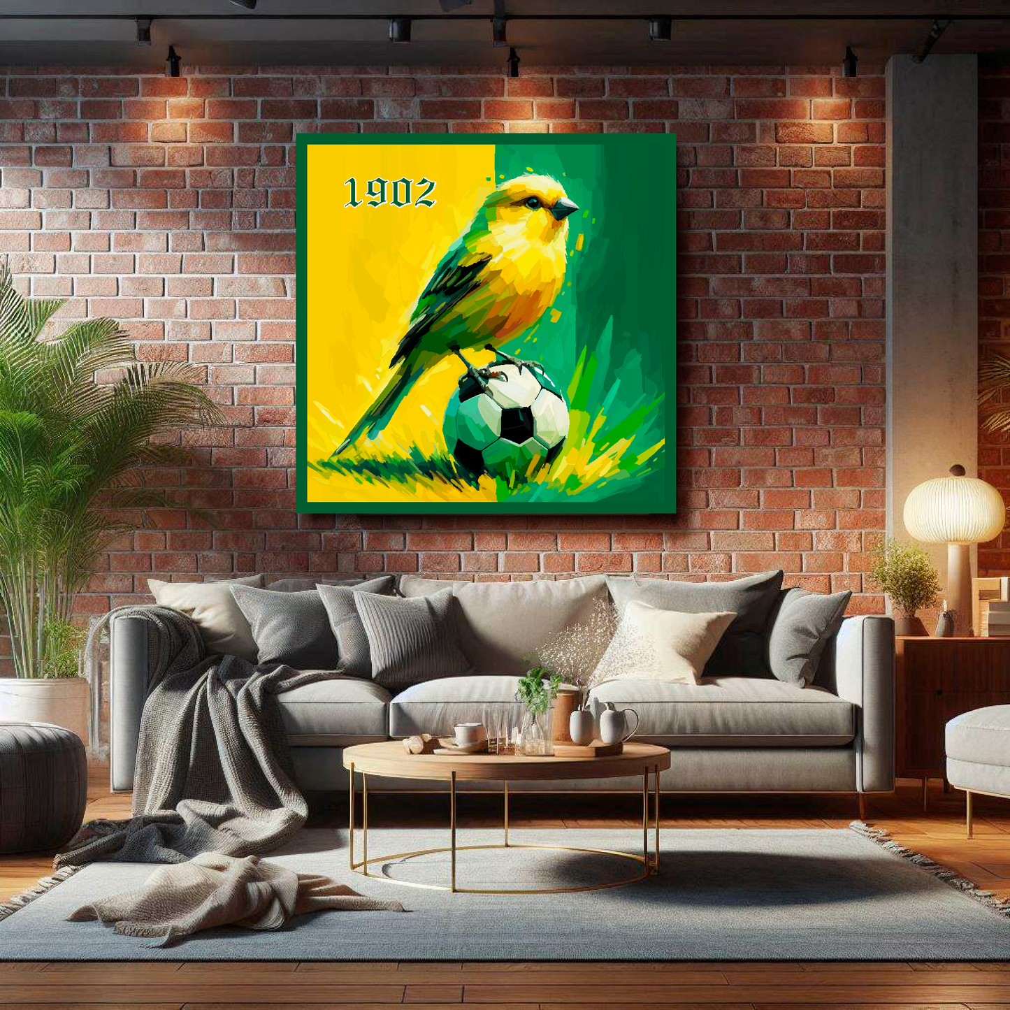 Norwich City FC inspired canvas, mounted on a brick living room wall above a grey sofa, featuring a Canary sitting on a football on a Yellow and Green halved background. '1902' in top left hand corner.
