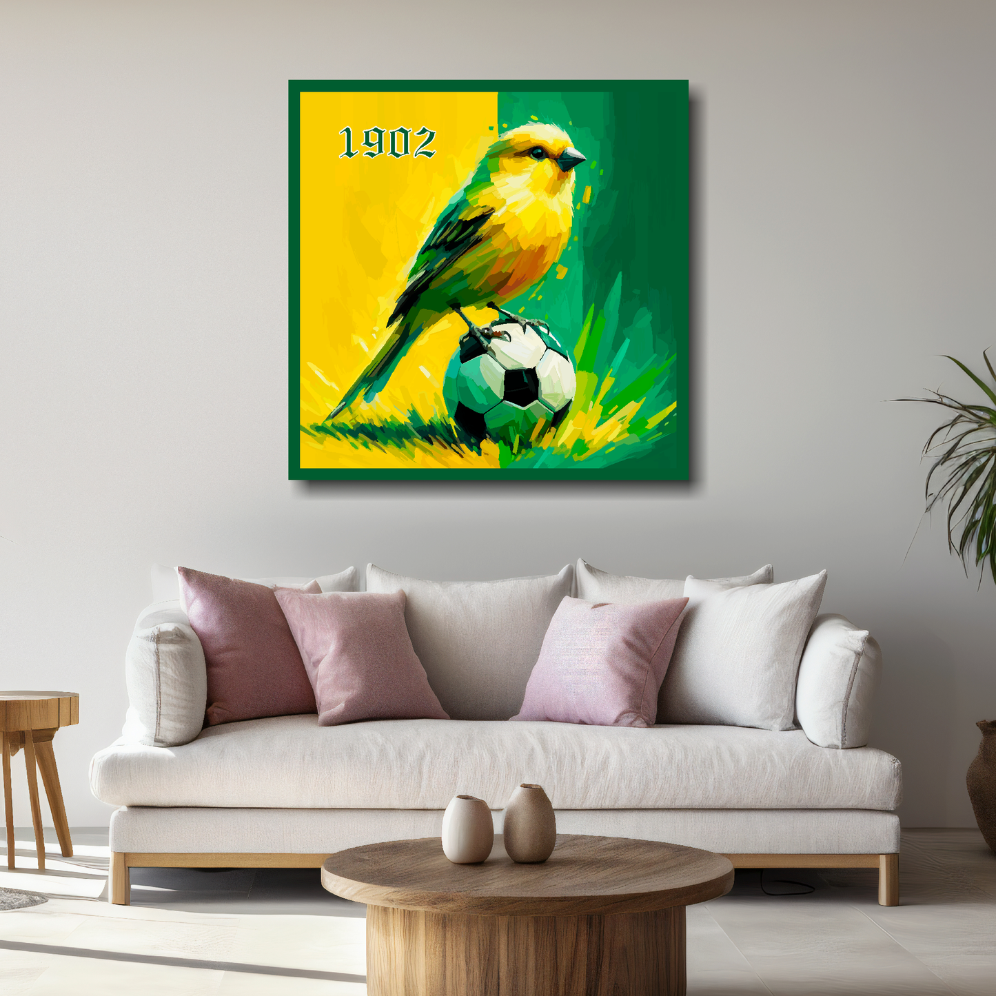 Norwich City FC inspired canvas, mounted on a white living room wall above a sofa, featuring a Canary sitting on a football on a Yellow and Green halved background. '1902' in top left hand corner.
