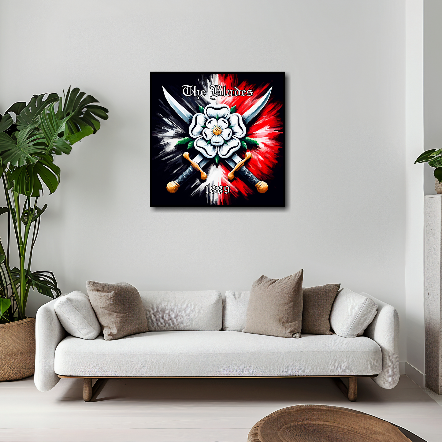 20 inch by 20 inch Sheffield United FC inspired canvas, mounted on a living room wall above a white sofa. Featuring two crossed swords with a white Yorkshire rose on a black and red background. 'The Blades' written at the top with '1889' at the bottom.