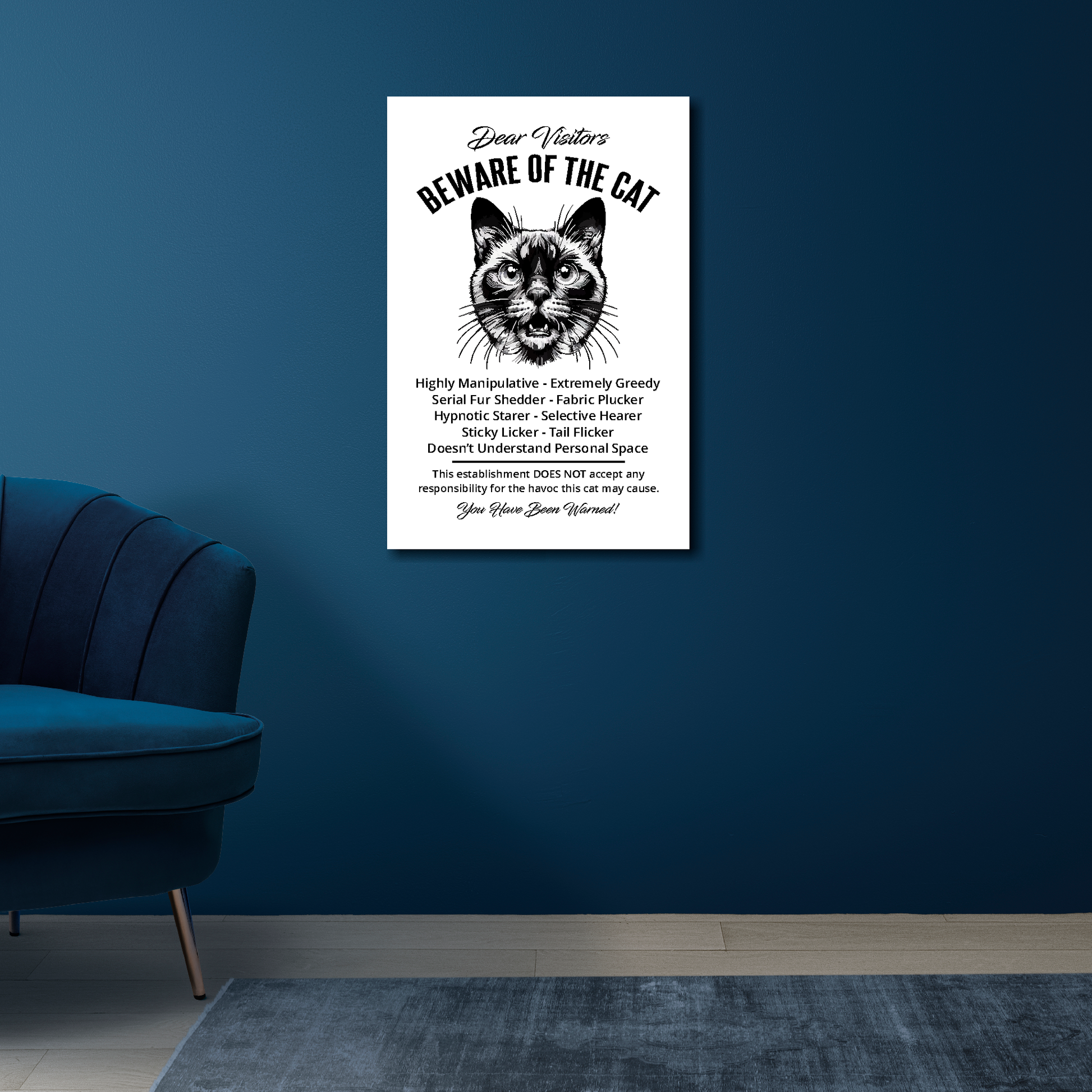 16 inch by 24 inch canvas print of a funny Siamese 'Beware of the cat' notice. Mounted on a blue wall above a blue chair.