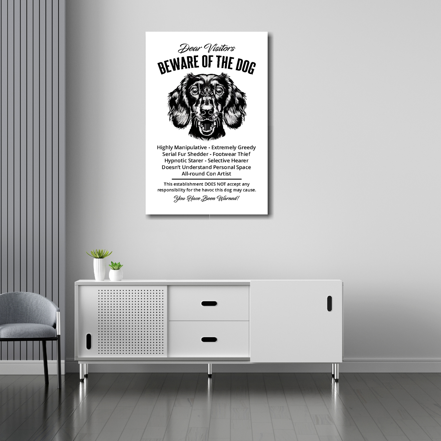 20 inch by 30 inch canvas print of a funny Longhaired Dachshund 'Beware of the Dog' notice. Mounted on a gray wall above a white sideboard.