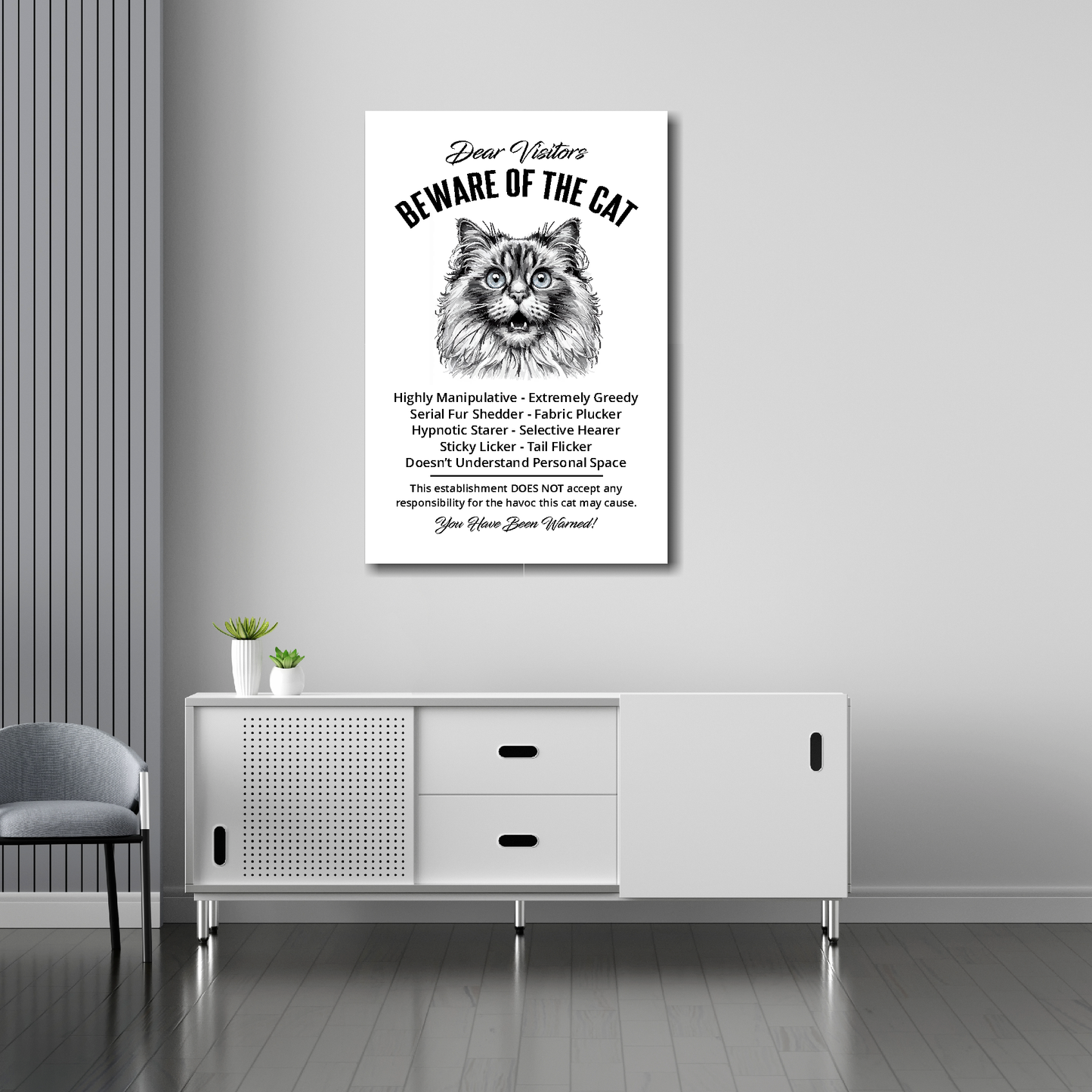 20 inch by 30 inch canvas print of a funny Ragdoll 'Beware of the cat' notice. Mounted on a gray wall above a white sideboard.