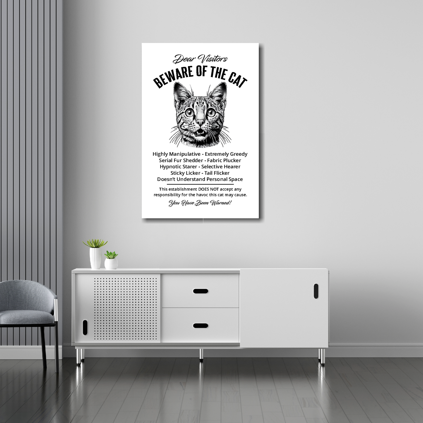 20 inch by 30 inch canvas print of a Savannah 'Beware of the cat' notice. Mounted on a gray wall above a white sideboard.