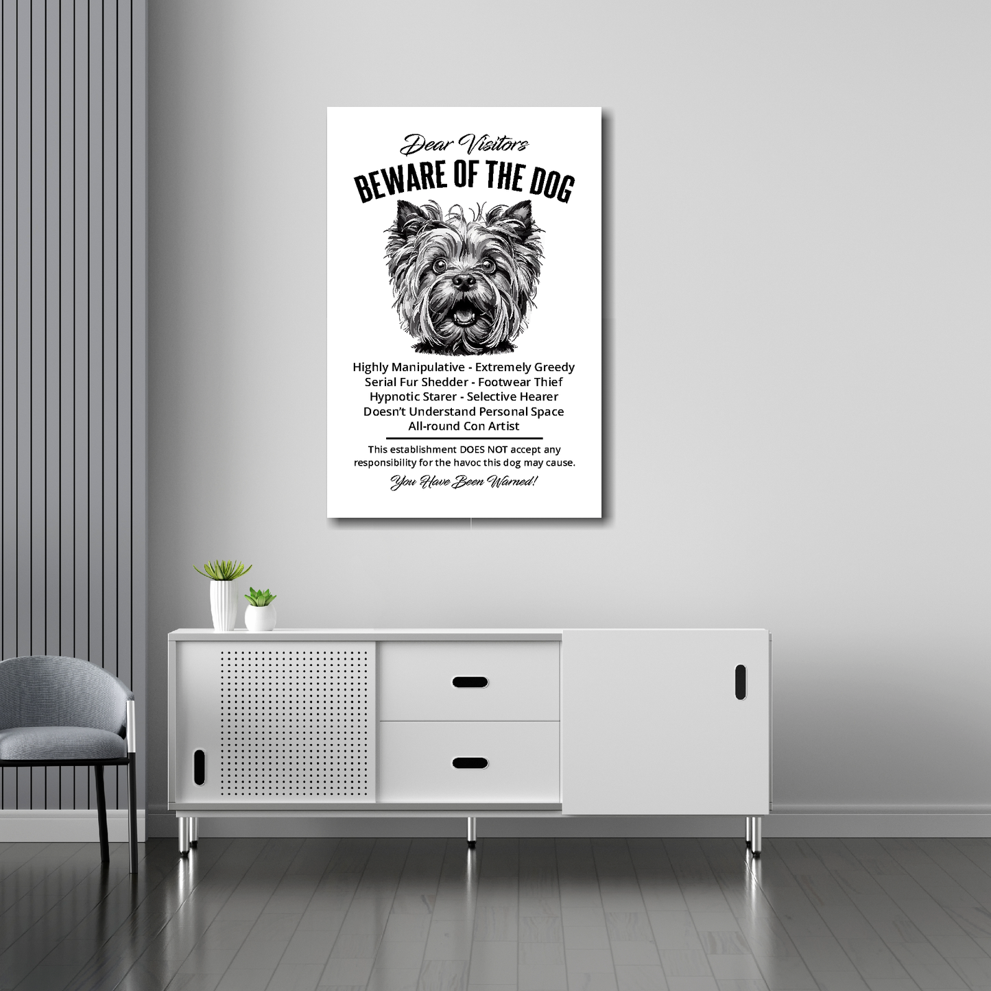 20 inch by 30 inch canvas print of a funny Yorkshire Terrier 'Beware of the Dog' notice. Mounted on a gray wall above a white sideboard.