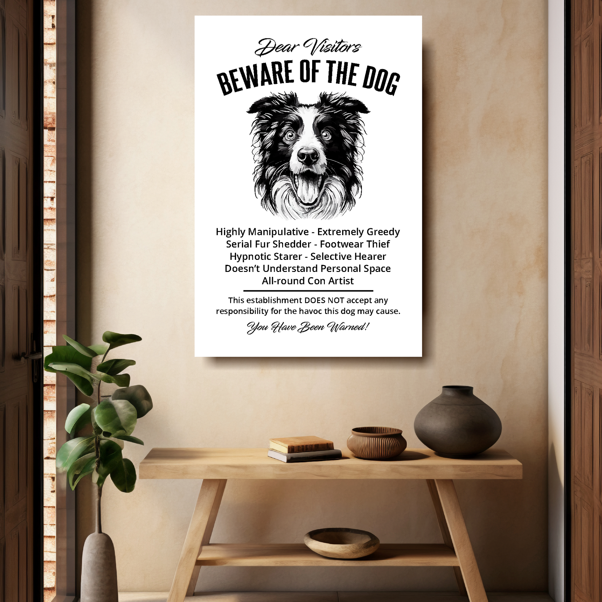 A funny Border Collie 'Beware of the Dog' disclaimer notice. Black text and dog image on a white background. Mounted on a beige wall above a wooden bench.