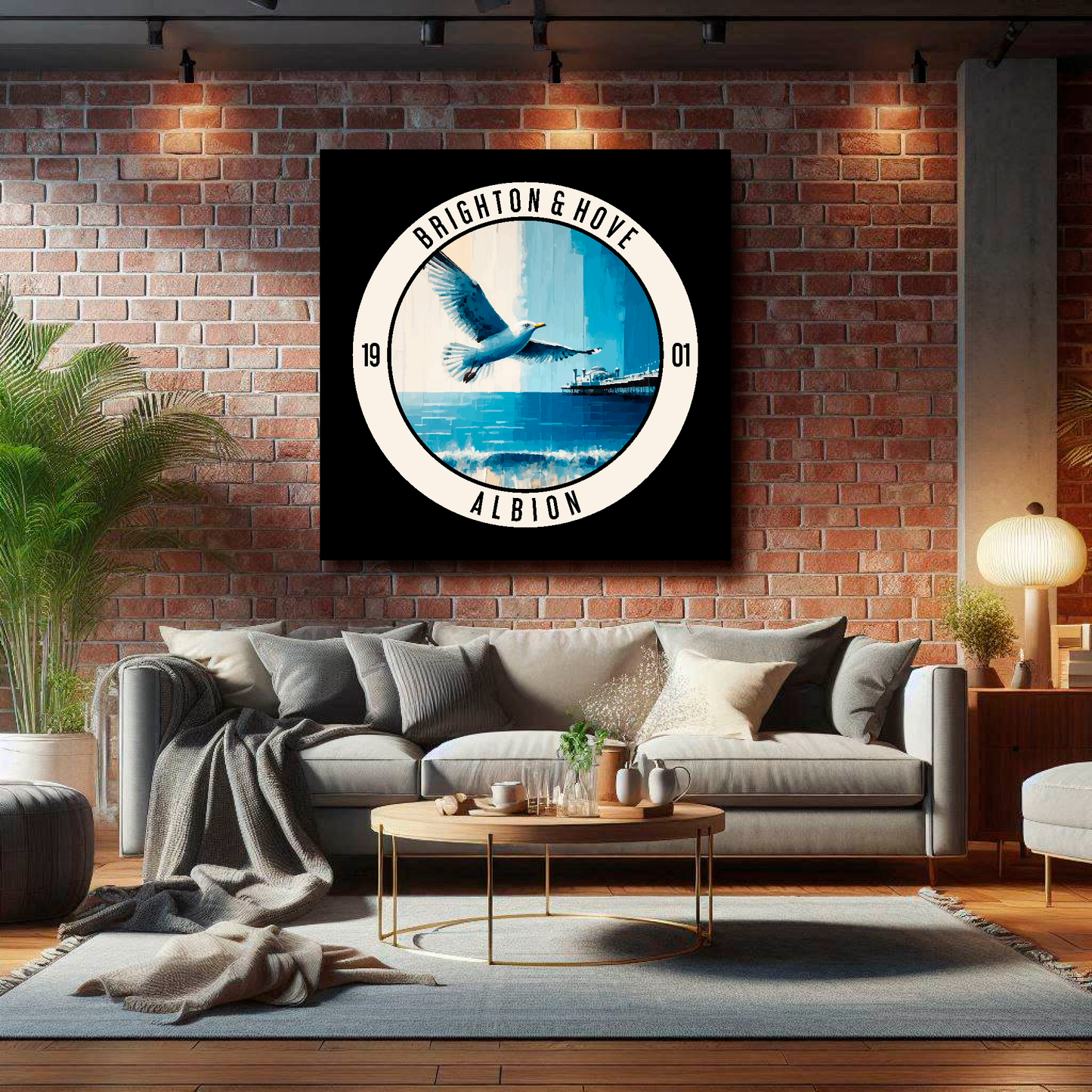 Brighton FC inspired canvas, featuring a large seagull, beach and pier on black background. Mounted on a brick wall above a grey sofa with decorative cushions.