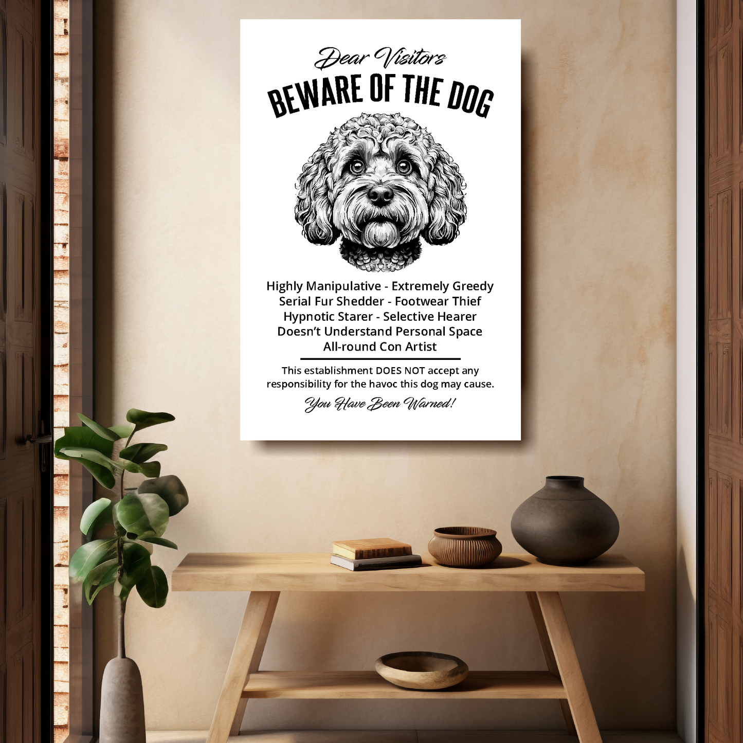 A funny Cockapoo 'Beware of the Dog' disclaimer notice. Black text and dog image on a white background. Mounted on a beige wall above a wooden bench.