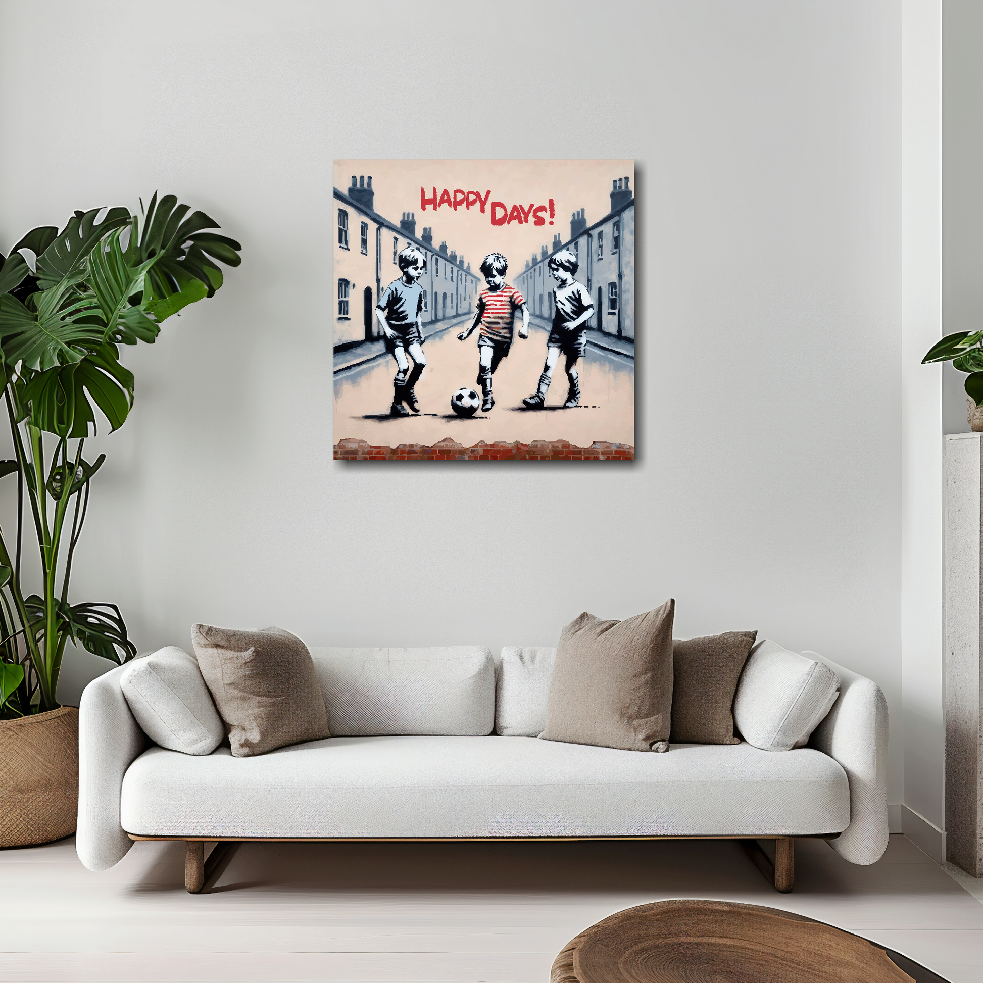 20 inch by 20 inch square canvas featuring three young boys playing football in the street, text at the top saying...'Happy Days'. Mounted on a white wall above a white sofa with decorative pillows.