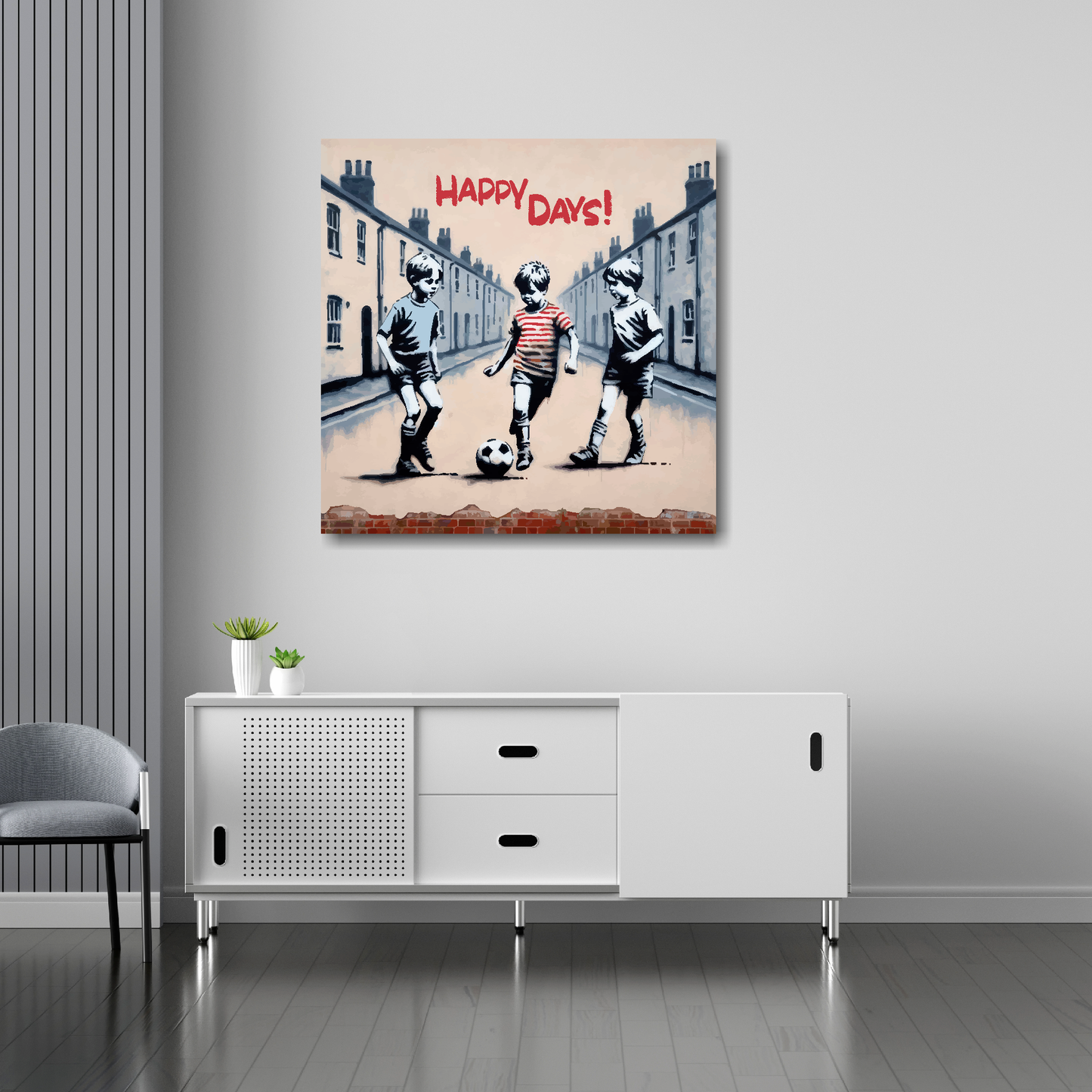 30 inch by 30 inch square canvas featuring three young boys playing football in the street, text at the top saying...'Happy Days'. Mounted on a white wall above a white sideboard.