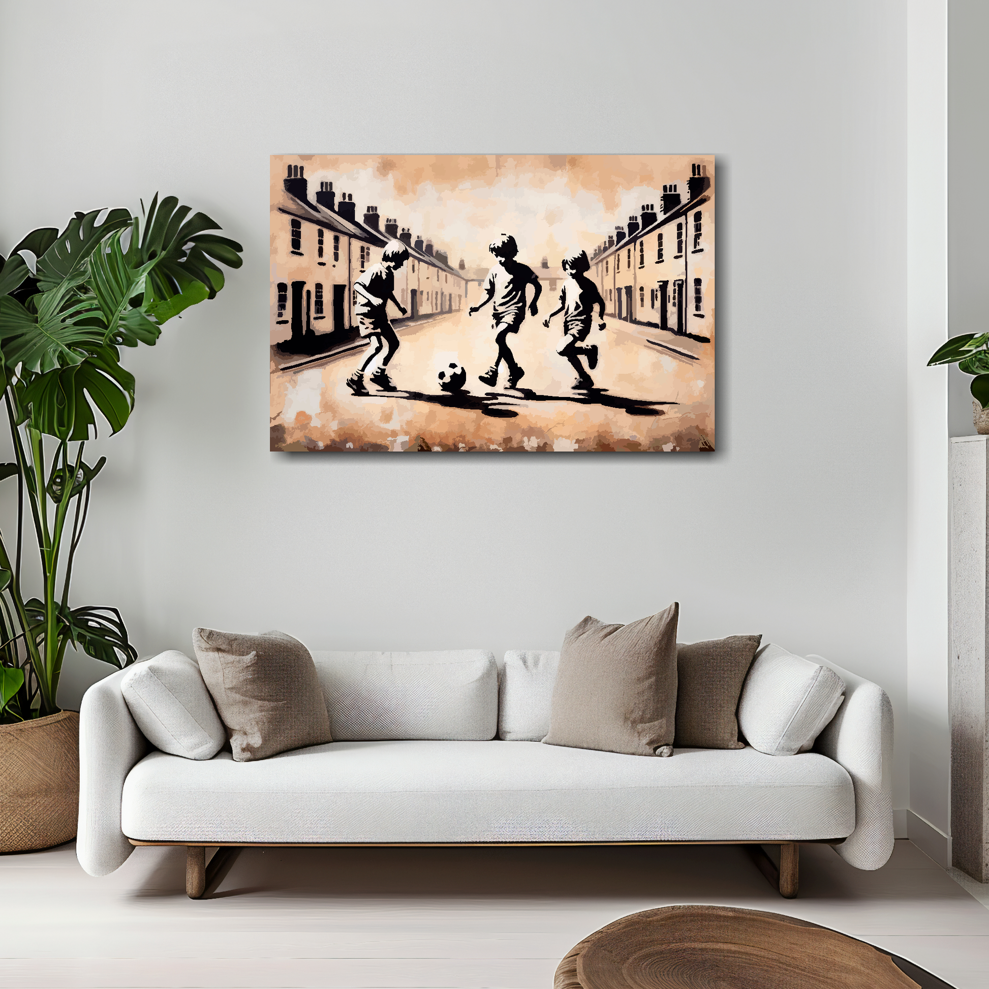 30 inch by 20 inch abstract canvas print of three boys playing fooball in the street. Mounted on a white wall above a white sofa with decorative pillows.