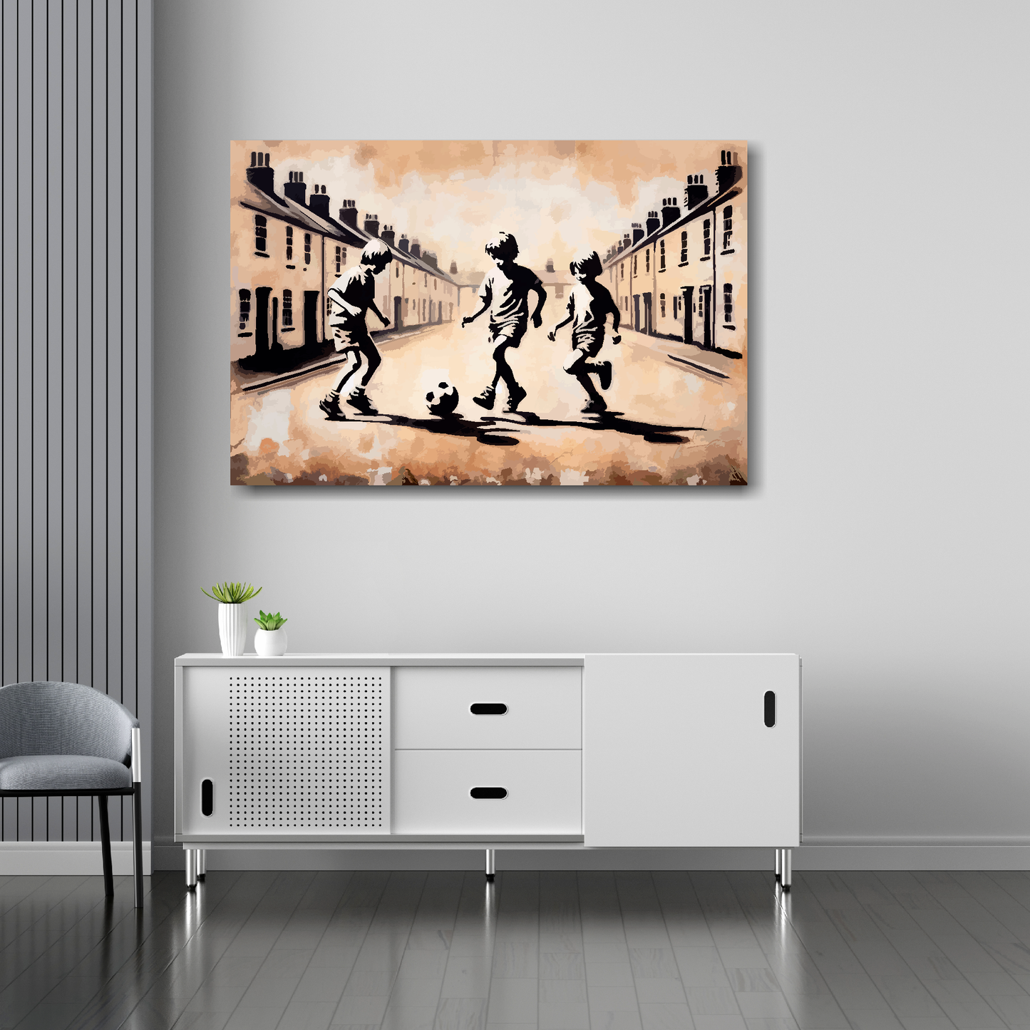 36 inch by 24 inch abstract canvas print of three boys playing fooball in the street. Mounted on a white wall above a white sideboard.